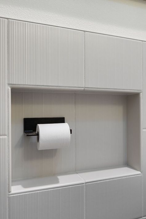 Our client was sick of hitting his knee on the toilet paper holder. So, when it came time to remodel his bathroom, he loved the idea of building a niche to recess the toilet paper holder, so he didn't constantly hit his knees. Plus, he can store an extra roll of toilet paper right there – how efficient! We had to ensure that the niche was big enough and worked with our tile installer, so the layout worked with the tile layout. Toilet Paper Niche, His And Her Bathroom, 1970s Bathroom, His Bathroom, His And Hers Bathroom, Recessed Toilet Paper Holder, Her Bathroom, Tile Layout, Bathroom Remodels