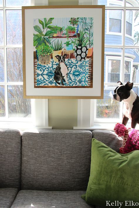 Love this custom colorful pet painting with tips on how to hang art on windows kellyelko.com #petart #dogart #dogpainting #petportrait #plantlady #plants #sunroom #sunroomdecor #bostonterrier Art Hung In Front Of Window, Art Hung On Window, Art In Front Of Window, Hanging Art Over Window, Art Between Two Windows, Art Between Windows, Art On Windows, Plants Sunroom, Pet Photo Wall Decor