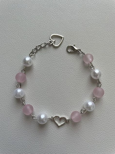 This handmade bracelet is the perfect blend of vintage and modern. With its delicate pink and white beads, silver heart charms, and dainty chain, it's sure to add a touch of sweetness to any outfit. Whether you're celebrating Valentine's Day, friendship, or just want to treat yourself, this bracelet is the perfect accessory. Coquette White, Bracelets Cute, Pink Beaded Bracelet, Cute Friendship, Pink Beaded Bracelets, Cute Friendship Bracelets, Aesthetic Rings, Dainty Chain, Bracelet Collection