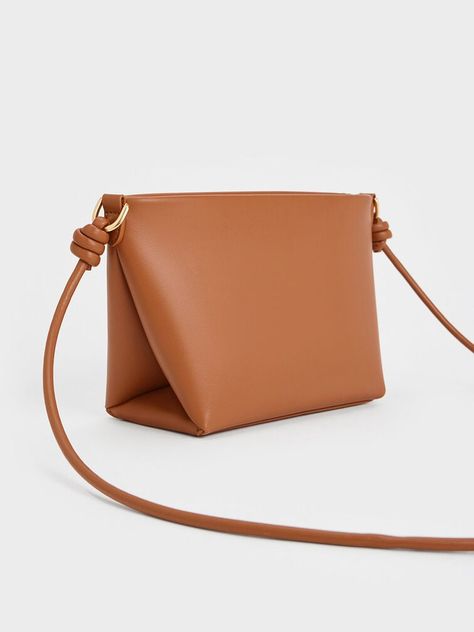 This product is made with at least 20% sustainable materials by weight. CHARLES & KEITH uses recycled, degradable, organic, and water-based materials in our eco-conscious collection. From the luxurious tan finish to the intricate details, this Midori bag will be a stunning addition to your wardrobe. Featuring eye-catching geometric folds and complementary sculptural knots on the straps, this striking design balances distictive details with a clean, elegant silhouette. Equipped with a zip closure that will keep your valuables secure, it is a stylish and practical carrier that will elevate any outfit you pair it with. Fold Over Bag Pattern, Leather Bag Pattern, Lovely Places, Brand Collaboration, Size Chart For Kids, Charles Keith, Printables Kids, Sustainable Materials, Cosmetic Bags