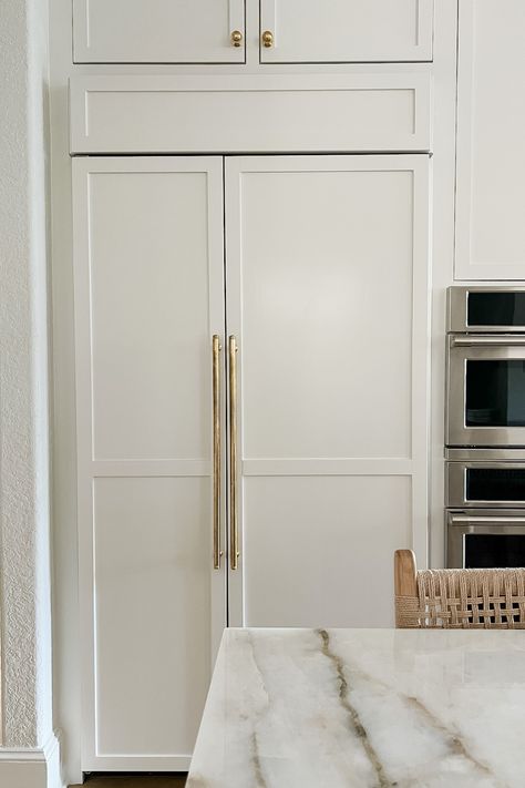 Looking for ideas for a built-in fridge? This refrigerator blends seamlessly into the cabinets and also makes a statement with brass hardware. Click here to see more kitchen design ideas from this project! Beautiful Kitchens Refrigerator, Built In Column Fridge And Freezer, Built In Upright Freezer, Refrigerator That Looks Like Cabinets, Refrigerator Handles Gold, Fridge With Cabinet Doors, Refrigerator Built In Cabinet, Cabinet Fridge Built Ins, Refrigerator Next To Wall