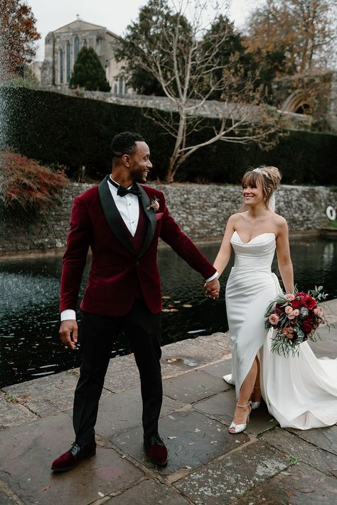 Bride in strapless wedding dress with sparkly Jimmy Choo wedding shoes with the groom in a red velvet suit jacket for their couple portraits Christmas Wedding Tuxedo Groomsmen, Christmas Wedding Groomsmen Green, Christmas Wedding Attire, Christmas Wedding Picture Ideas, Red Velvet Suit Mens Wedding, Christmas Wedding Photos, Black And Red Tux, Velvet Groom Suit, Ruby Red Groomsmen