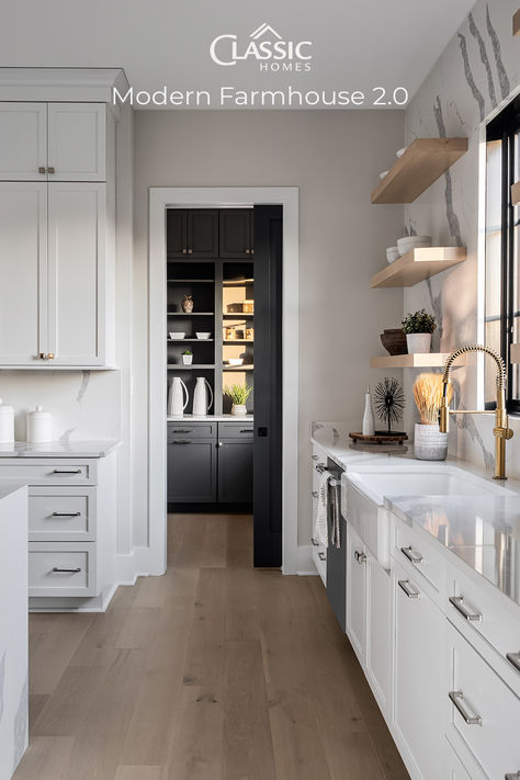 A kitchen detail photo showing the Butler's Pantry sliding door open in the center focal point, dark cabinets contrast with the light kitchen in the foreground, showing white quartz counters and accent wall. Backsplash With Floating Shelves, Farmhouse Sink Black, Marsh Cabinets, Modern Farmhouse Style Kitchen, Kitchen Butlers Pantry, Classic Homes, Architectural Photographers, Black Windows, Bath Ideas