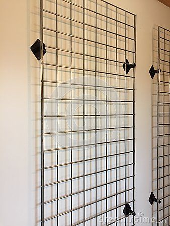 Silver metal grid with black metal holders used for hanging display items on. Never put holes in the walls again. Great to hang pictures on. Grid Wall Clothing Display, Grid Wall Retail Display, Grid Wall Design, Gridwall Display Ideas, Metal Grid Wall Decor, Wall Grid Ideas, Wire Grid Wall Display, Wire Grid Wall, Metal Wall Grid