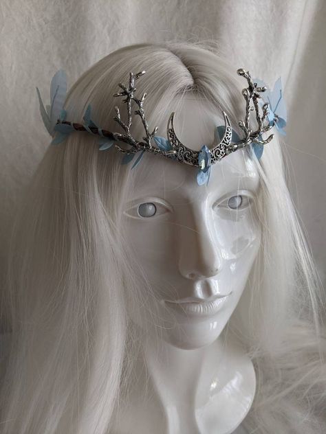 This gorgeous tiara features a filigree crescent moon, a sparkling opalescent blue crystal in the center, and branches on either side. Fallen sky blue leaves surround the flexible branch-like base and large blue leaves adorn each side. This piece is adjustable with a ribbon tie in the back. Choose between a silver moon and branches as pictured or bronze! Silver Moon Crown, Moon Elf Cosplay, Moon Fantasy Outfit, Blue Head Accessories, Woodland Tiara, Blue Tiara, Moon Clothing, Ethereal Jewelry, Elf Cosplay