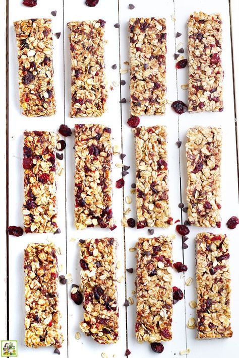 Homemade granola bars made with chocolate chips, oatmeal, and dried cranberries on a white wooden board. Basic Granola Bar Recipe, Cranberry Granola Bars, Homemade Oatmeal Bars, White Chocolate Chips Recipes, Lactation Granola, Oatmeal Granola Bars, Homemade Granola Bar Recipe, Cherry Granola, Granola Bars Recipe