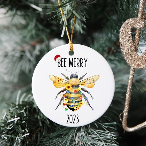 "This sweet honey bee ornament is perfect for the holiday season!  It features a cute honey bee with some Christmas lights and the quote \"Bee Merry,\" which is sure to bring a smile to your face. Plus, the current year is also displayed, so you can always remember what year it was added to your Christmas decor collection.  This is a great ornament for anyone who loves honey bees! ABOUT Design your own set of Christmas decorations to make your tree hip, traditional, or funky to suit your unique Bee Ornaments Christmas, Bumble Bee Gift Ideas, Honey Bee Ornaments Diy, Bee Christmas Card, Christmas Bees, Bee Christmas Tree, Bee Ornaments, Christmas Bee, Bee Christmas