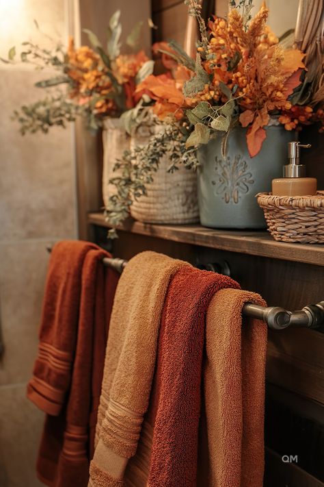 Cozy fall bathroom decor with warm-toned towels and vibrant autumn flowers in rustic containers. Perfect fall bathroom decoration ideas for your home. Bathrooms Decorated For Fall, Bathroom Decor Earth Tones, Fall Aesthetic Bathroom, Fall Decor In Bathroom, Blue Fall Bathroom Decor, Cozy Fall Decor Bathroom, Antique Bathroom Decor Ideas, Rust And Blue Bathroom, Fall Decorations Bathroom