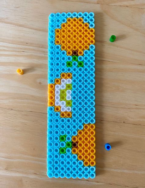 A beaded bookmark made from perler beads in an orange pattern, the perfect gift for any book-lover. Perler Bead Bookmarks Pattern, Perler Bookmark, Perler Beads Bookmark, Perler Bead Bookmarks, Harry Potter Perler Beads, Beaded Orange, Geek Christmas, Perler Ideas, Easy Perler Beads Ideas