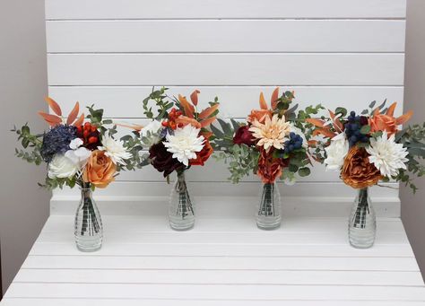 These gorgeous centerpieces feature a mix of warm autumn hues like burnt orange, ivory, and deep burgundy, accented by touches of eucalyptus and blue berries. Perfect for adding a rustic, cozy feel to your wedding or special event! 🍂✨ #AutumnWedding #RusticCenterpiece #FauxFlowers #WeddingDecor #FallDecor #Centerpieces #weddingflorist Bouquet Fall Wedding, Ivory Bouquet, Faux Bouquet, Mini Bouquets, Boho Wedding Flowers, Gorgeous Centerpieces, Groom Accessories, Faux Flower Arrangements, Rustic Centerpieces