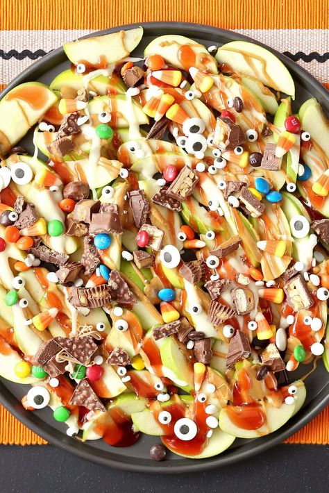 Put all that Halloween candy to good use by whipping up a tray of these dessert nachos. Top sliced Granny Smith apples with melted peanut butter, jelly, and chopped chocolate candy. A sprinkle of candy eyes adds a spooky touch. #halloweenrecipes #halloweentreats #halloweensnacks #halloweenpartyfood #bhg Halloween Potluck Recipes, Halloween Food Snacks, Halloween Potluck, Dessert Nachos, Halloween Finger Foods, Finger Foods For Kids, Halloween Charcuterie, Halloween Apples, Apple Nachos