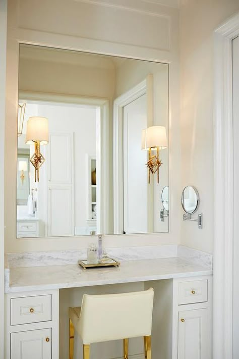 Lovely white and ivory bathroom features an ivory leather stool on gold legs placed at a white built-in makeup-vanity accented with brass hardware and topped with a white marble countertop. Makeup Vanity Built In, Makeup Vanity In Closet, Built In Makeup Vanity, Built In Bedroom, Bathroom Vanity Stool, Vanity Nook, Makeup Vanity In Bathroom, Vanity In Bedroom, Vanity In Bathroom