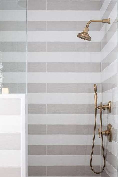 A brass shower kit is mounted against gray striped shower surround tiles. Ceiling Shower Head, Grey Wall Tiles, Striped Tile, Subway Tiles Bathroom, Shower Wall Tile, Drop In Bathtub, White Tub, Shower Floor Tile, Transitional Bathroom