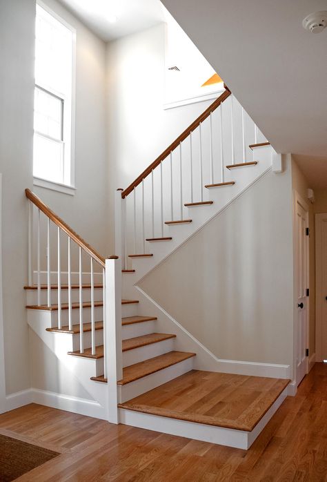 Photo of a scissor stair with wood balusters and square newel posts. The newel posts feature a round custom cap.