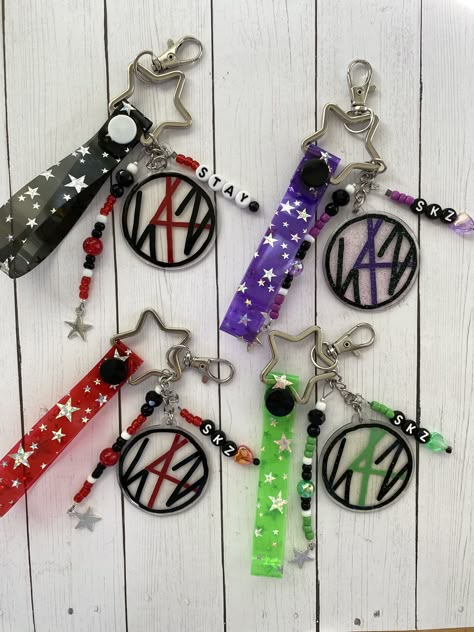 One of my most popular pieces has gotten an upgrade! This Stray Kids keychain is now available in 4 different colors: black, red, green, and purple! the green and purple Maniac inspired pieces have glitter on them 😍 As each piece is made to order- leave a note to me when purchasing if you don't want glitter - or DO want glitter added to a black or red charm.  Each finished keychain measures ~5" long from hook to end of hand tag. The logo charm is hand painted by me and sealed with resin.  *Bead and button colors may vary slightly but will be about the same style as shown* Please contact me if you have any questions or customization requests. I'd love to help you get a custom piece you'll love!  *Please refrain from forcefully pulling or tugging on keychains. Thank you.* Stray Kids Lightstick Decoration, Stray Kids Keychain, Stray Kids Clothes, Kpop Keychain, Skz Merch, Red Keychain, Pop Jewelry, Jewels Diy, Stray Kids Kpop