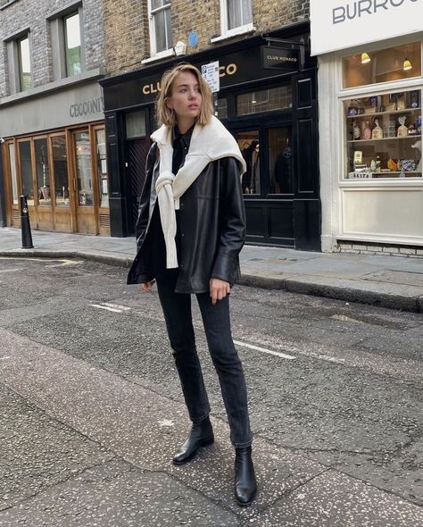 Lizzy Hadfield in a black jacket, beige sweater tied over the shoulders, black jeans, and flat pointed-toe boots. Mode Dope, Yoo Ah In, Faded Black Jeans, Look Casual Chic, Looks Street Style, Instagram Outfits, Leather Shirt, 가을 패션, Outfits Fashion