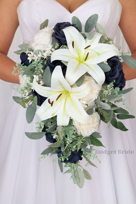 This brides’ bouquet is the perfect option if you have chosen a classic theme for your wedding. A lovely array of neutral white lilies and ivory peonies are center-stage in this stunning arrangement. Navy blue roses and greenery complete this romantic and beautiful design. As always, this bouquet has been wired by hand and designed by our in-house florists - you can rest assured that our bouquets will maintain their quality and stand the test of time for years to come. We never use foam to ancho Navy And Sage Wedding Bouquet, Rustic Elegant Wedding Bouquet, Hydrangea Lily Bouquet, Shades Of Blue Wedding Bouquet, Hydrangea And Lily Bouquet, Bridal Bouquet With Lilies, Lillys Flowers Bouquet, Wedding Bouquet With Lilies, Blue And White Wedding Bouquets