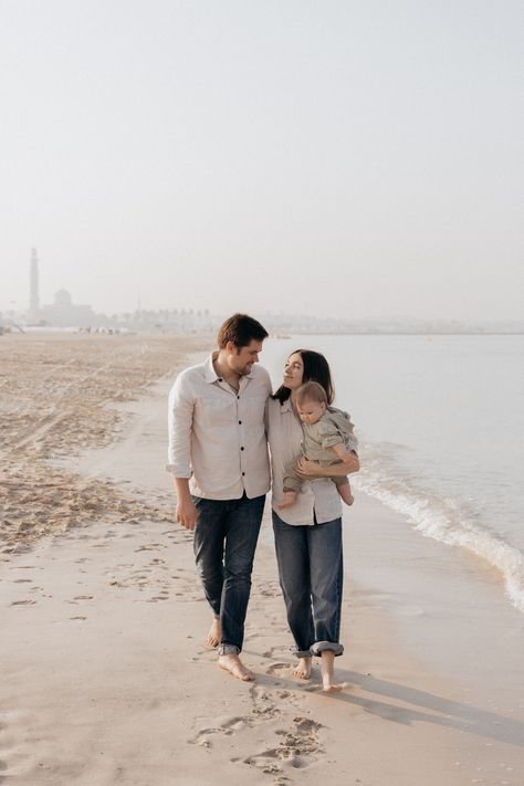 A family walking on the beach, with parents smiling and enjoying the moment while holding their baby, capturing a joyful family outing. Photoshoot Dubai, Family Beach Photoshoot, Morning Photoshoot, Beach Photoshoot Ideas, Family Walking, Photo Album Gift, Fresh Morning, Newborn Birth, Creative Poses