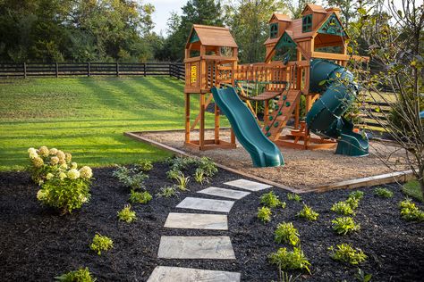 Outside children's playset and stepping stones Playset In Corner Of Yard, Backyard Design With Playset, Play Set Landscaping Backyard Playground, Playset Landscaping Ideas, Home Playground Landscaping, Playground Area Landscape, Mulch Play Area For Kids, Outdoor Playset Landscaping, Backyard With Playset