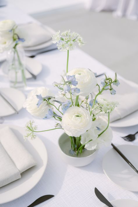 Get inspired by this elegantly set table, perfect for bridal shower ideas! The minimalist floral arrangement with pristine white ranunculus and delicate blue sprigs complements the crisp white plates and linen napkins. 🌸✨ The modern black-handled knives add a chic touch to this tranquil setup. Check out more 🌿 #weddingcenterpieces #bridalshower #wedding #beachwedding #tablescapeideas Minimalist Flower Arrangement, Coastal Wedding Centerpieces, Boho Table Setting, Bud Vases Wedding, Pale Blue Flowers, Floral Table Setting, Bud Vase Centerpiece, Blue Flower Arrangements, Blue Wedding Receptions