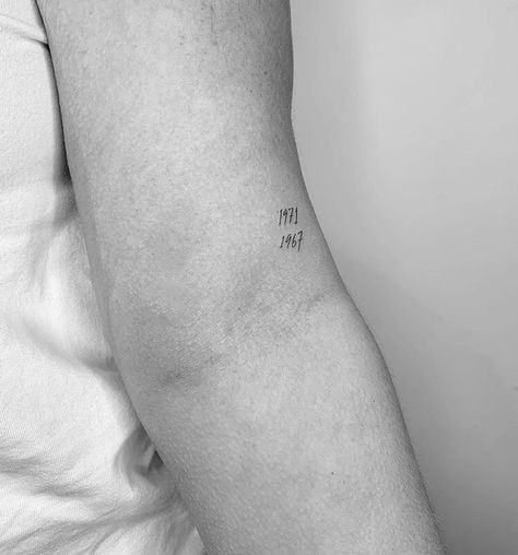 Above Back Of Elbow Tattoo, Minimalist Grandparents Tattoo, Simple Birth Year Tattoo, Year Dates Tattoo, Tiny Birthday Tattoos, Delicate Date Tattoo, Fine Line Year Tattoos, Creative Number Tattoo, Fine Line Tattoos Meaningful