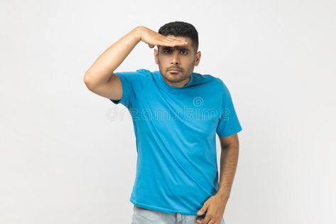 Man keeps hand near forehead looks far away, searches something on horizon. stock photography Hand On Forehead, Hunter Gatherer, Vector Banner, Men Looks, Blue Tshirt, Pose Reference, Stock Photography, Photo Image, Acting