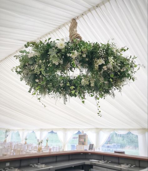 Create a statement with a hanging floral installation. This 5ft diameter floral chandelier worked perfectly decorating the marquee and the bar area Hanging Flower Arrangements Wedding, Hanging Wreaths From Ceiling, 1910s Farmhouse, Flowers Hanging From Ceiling Wedding, Floral Chandelier Diy, Chandelier Greenery, Hanging Floral Arrangements, Wedding Lights Decor, Marquee Wedding Decoration