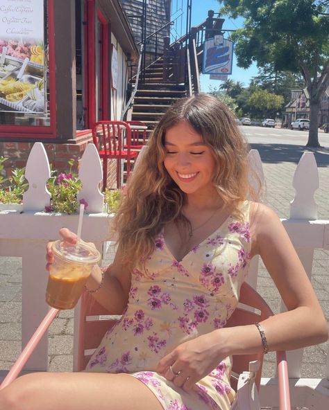 Girl sitting in a light pink chair holding a coffee and looking down. She is wearing a princess Polly yellow dress with purple flowers. Location: solvang, California Solvang California, California Aesthetic, Aesthetic Poses, Dress Lavender, Mini Skirt Dress, Instagram Coffee, La Girl, Coffee Date, Flower Dress