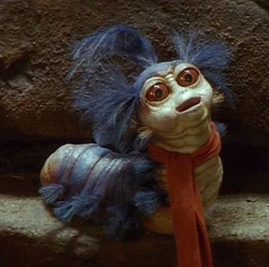 The worm is a small creature who lives in Jareth's Labyrinth, and is a featured character in the film of the same name. The Worm was operated by Karen Prell, and was voiced by the late Timothy Bateson. The worm is extremely hospitable, and offers Sarah guidance when she is at the point of giving up her quest to save her brother. He has a cockney accent, and wears a bright red scarf. Labyrinth Worm, Labyrinth Jareth, Labyrinth Art, Labyrinth 1986, Labyrinth Movie, Goblin King, The Dark Crystal, Jim Henson, Tarzan