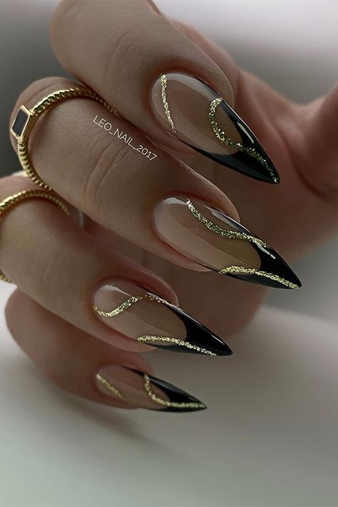 Classy stiletto black French tip nails with gold glitter swirl nail art Nails To Go With Black Outfit, Black Gold Tip Nails, Black French Tip Nails Almond With Gold, French Black Nail Designs, Black And Gold Tips Nails, Gel X Black French Tip, Wedding Nails Black And Gold, Gorgeous Almond Nails, Black Art Deco Nails