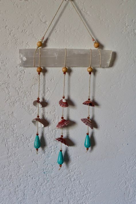 A unique and one of a kind handmade selenite crystal wand and sea shell wall art/windchime made with hand picked shells from Southern California, strung together with hemp cord and wood and glass beads. The perfect home decor addition to a Cottage-core, beachy or Boho Aesthetic. The selenite wand measures about 6 1/2 inches in length and 12 inches from top to bottom. Send me a message if you have any questions regarding this will hanging/windchime Visit my car charm shop section for additional designs and sunbather car charms. https://www.etsy.com/shop/RoseandWolves?ref=seller-platform-mcnav&section_id=38974068 Xoxo  Rose and Wolves Boho wall hanging, Shell wall decor, bedroom decor, boho gift, seashell hanging,  seashell art, minimalist decor, tropical room decor, Sea Shell Art, Coastal A Boho Hanging Decor, Sea Shell Wall Art, Seashell Hanging, Tropical Room Decor, Selenite Crystal Wands, Beachy Room Decor, Selenite Wand, Art Coquillage, Beachy Room