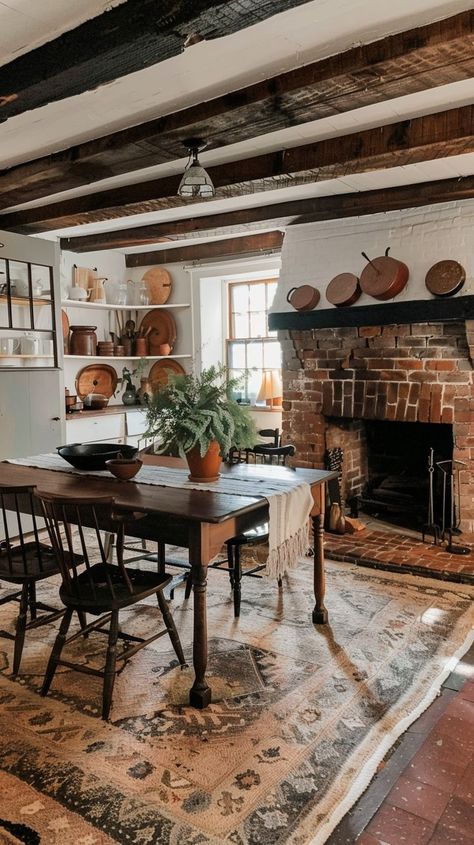 Cozy kitchen with exposed beams, brick fireplace, wooden dining table, and copper pots. Rustic and inviting space perfect for family gatherings. Brick Fireplace In Kitchen, Dining Room With Brick Fireplace, Fireplace In Dining Room, Fireplace Dining Room, Dining Room With Fireplace, Country Style Dining Room, Fireplace Dining, Red Brick Fireplaces, Inviting Kitchen