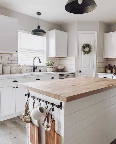 A modern farmhouse kitchen with greige walls and white cabinets features a white island with an ash butcher block countertop. Two black metal pendant lamps hang from the ceiling. The backsplash is of white subway tile...   Image: _littlebitofgrace_ Kitchen With Butcher Block Island, Kitchen Island With Butcher Block, Butcher Block Countertops Kitchen, Two Toned Kitchen Cabinets, Greige Kitchen, Kitchen Cabinets Ideas, Butcher Block Island Kitchen, Butcher Block Kitchen, Mobile Kitchen