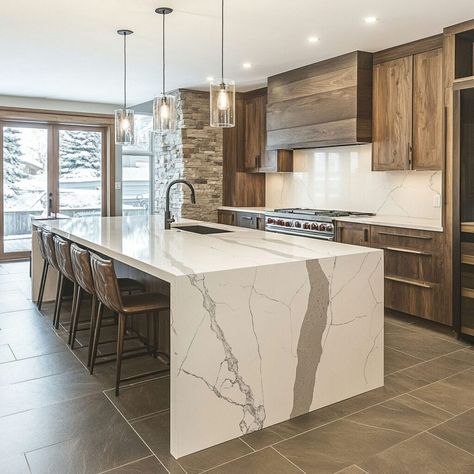 This stunning modern kitchen features a quartz waterfall island, highlighting the elegance and durability of quartz as a premium building material. With natural wood cabinetry and stone accent walls, the design blends warm wood tones with sleek, contemporary finishes. The quartz island serves as a focal point, perfect for social gatherings or culinary prep. Pendant lighting, open seating, and floor-to-ceiling windows complete this inviting space. Waterfall Edge Island, Quartz Waterfall Island, Loft Kitchen Ideas, Waterfall Kitchen Island, Wood Waterfall, Building Materials Architecture, Quartz Island, Waterfall Island Kitchen, Materials Architecture