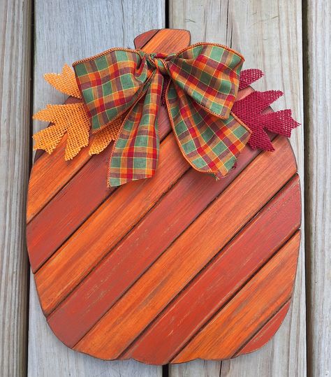 This handmade primitive rustic wooden Pumpkin sign is approximately 13"  x 10". It is made from pine boards which I have cut, painted, stained and distressed. It has a plywood  backing.  I've painted the entire piece various orange colors and then antiqued it. I've added a plaid bow and 2 leaves which can be removed. It has been finished with several coats of matte sealer.  This pumpkin comes with a picture hanger on the back so is ready to hang or it can simply rest on a shelf or mantle. Makes a great rustic, primitive Fall decoration! Painted Wood Pumpkins, Fall Mantel Decor, Halloween Wood Crafts, Troy Ny, Booth Displays, Picture Hanger, Rustic Pumpkin, Pine Boards, Primitive Fall