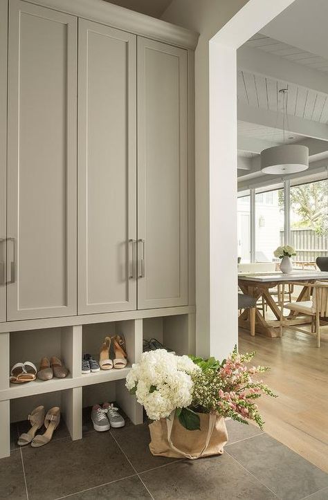 Gray mudroom features tall light gray closed lockers with nickel pulls fixed above stacked light gray shoe shelves fixed against slate floor tiles. Shoe Storage Narrow Hallway, Mudroom Cabinets, Slate Tile Floor, Mudroom Entryway, Mudroom Laundry Room, Entryway Shoe Storage, Entry Ways, Mudroom Design, Shoe Shelves