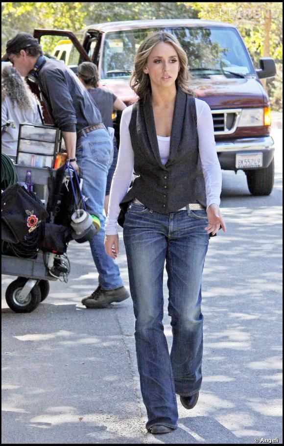 a woman is walking down the street in jeans