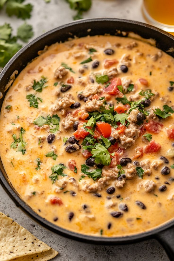 a black bean and rice soup in a skillet with tortilla chips on the side