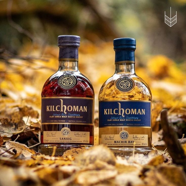 two bottles of kilchoman are sitting in the leaves