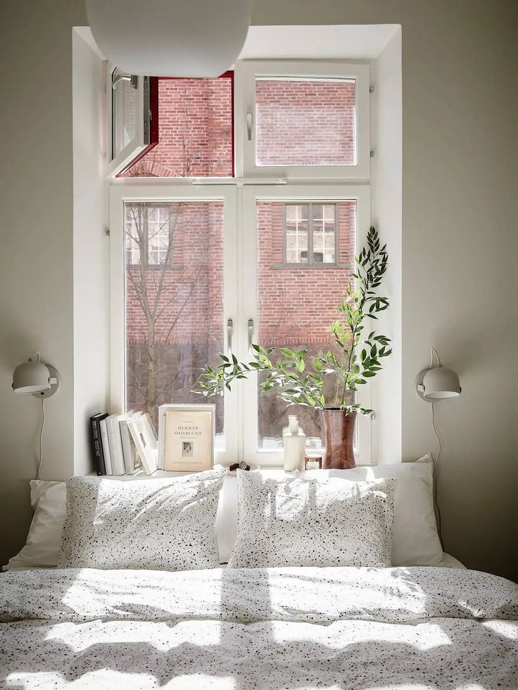 a bed with white sheets and pillows in front of a window filled with windowsills