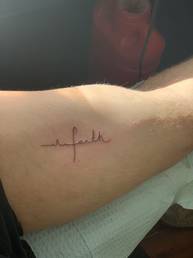 a man's arm with the word faith written in cursive writing on it