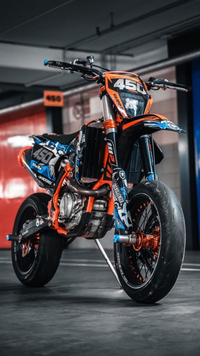 an orange and blue dirt bike parked in a garage