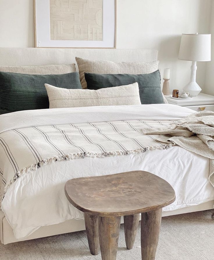 a bedroom with a white bed and two tables in front of the bed, along with pictures on the wall