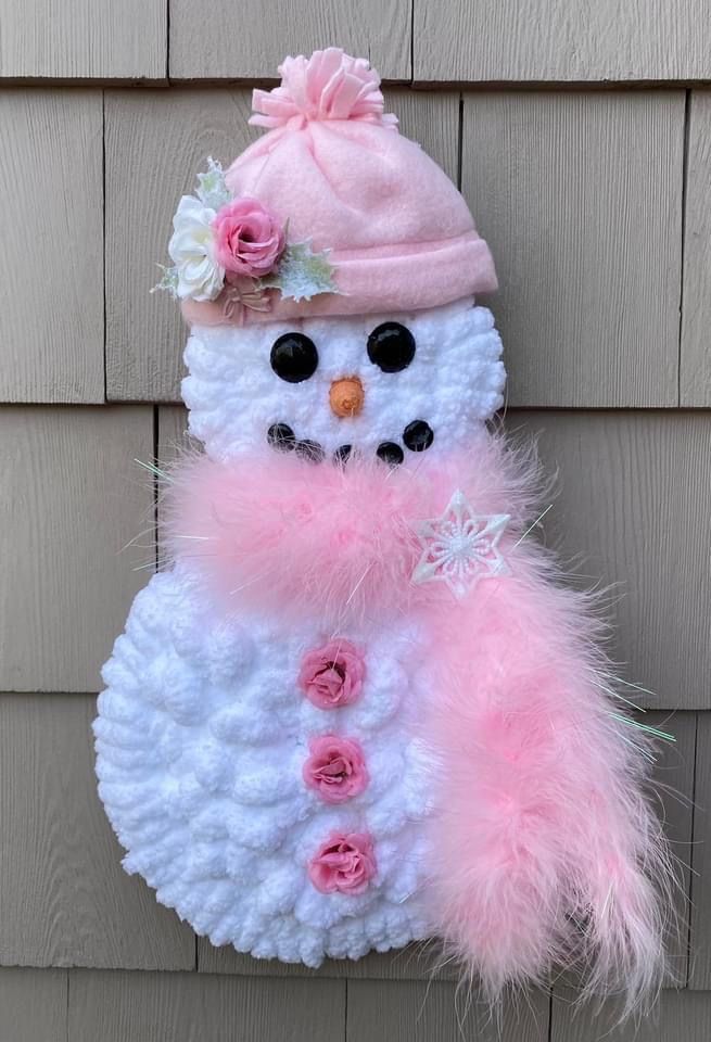 a crocheted snowman with pink and white flowers