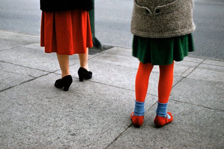 two women standing on the sidewalk with their legs crossed