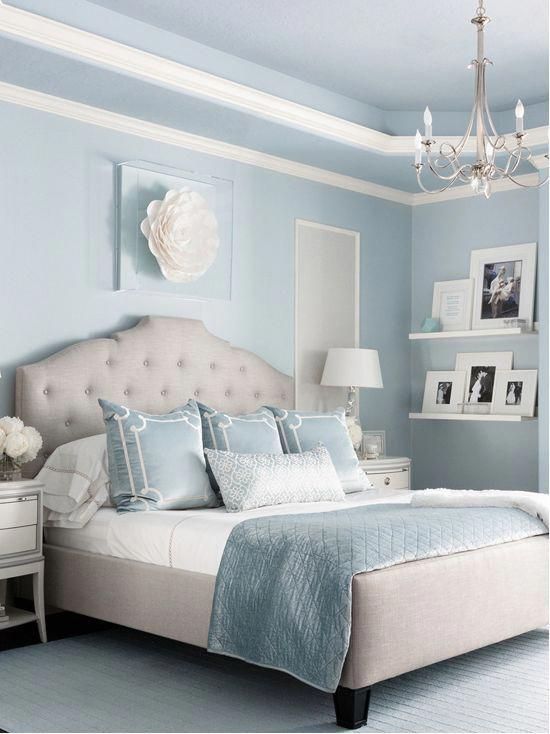 a bedroom with blue walls, white furniture and a chandelier hanging from the ceiling