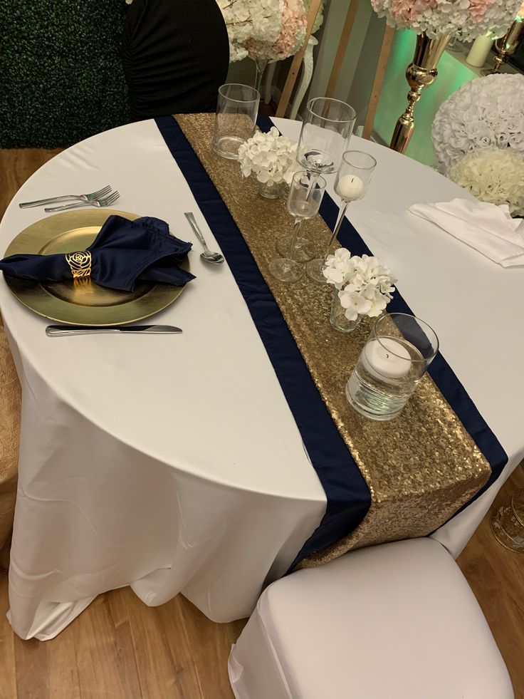 the table is set with white and blue linens, silverware, and flowers