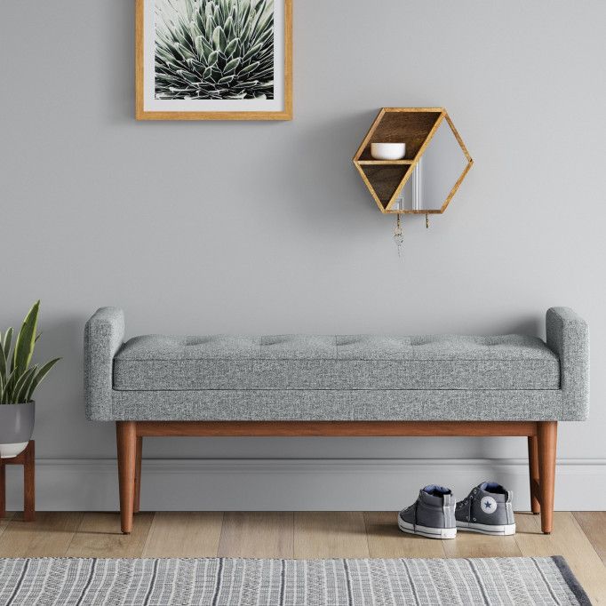 a living room with a bench, rug and potted plant on the wall next to it