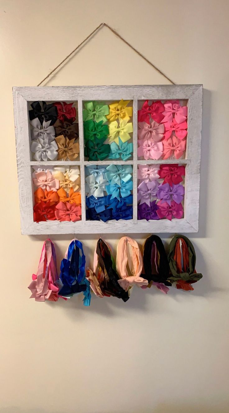 an old window is filled with different colored ribbons and bows hanging on the wall in front of it