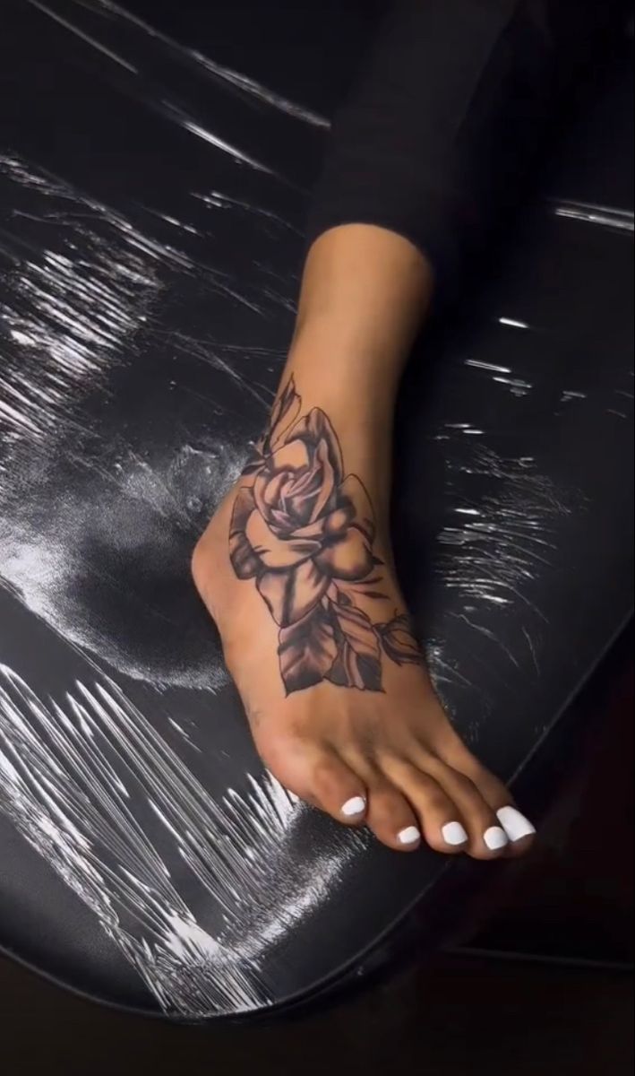 a woman's foot with a rose tattoo on it